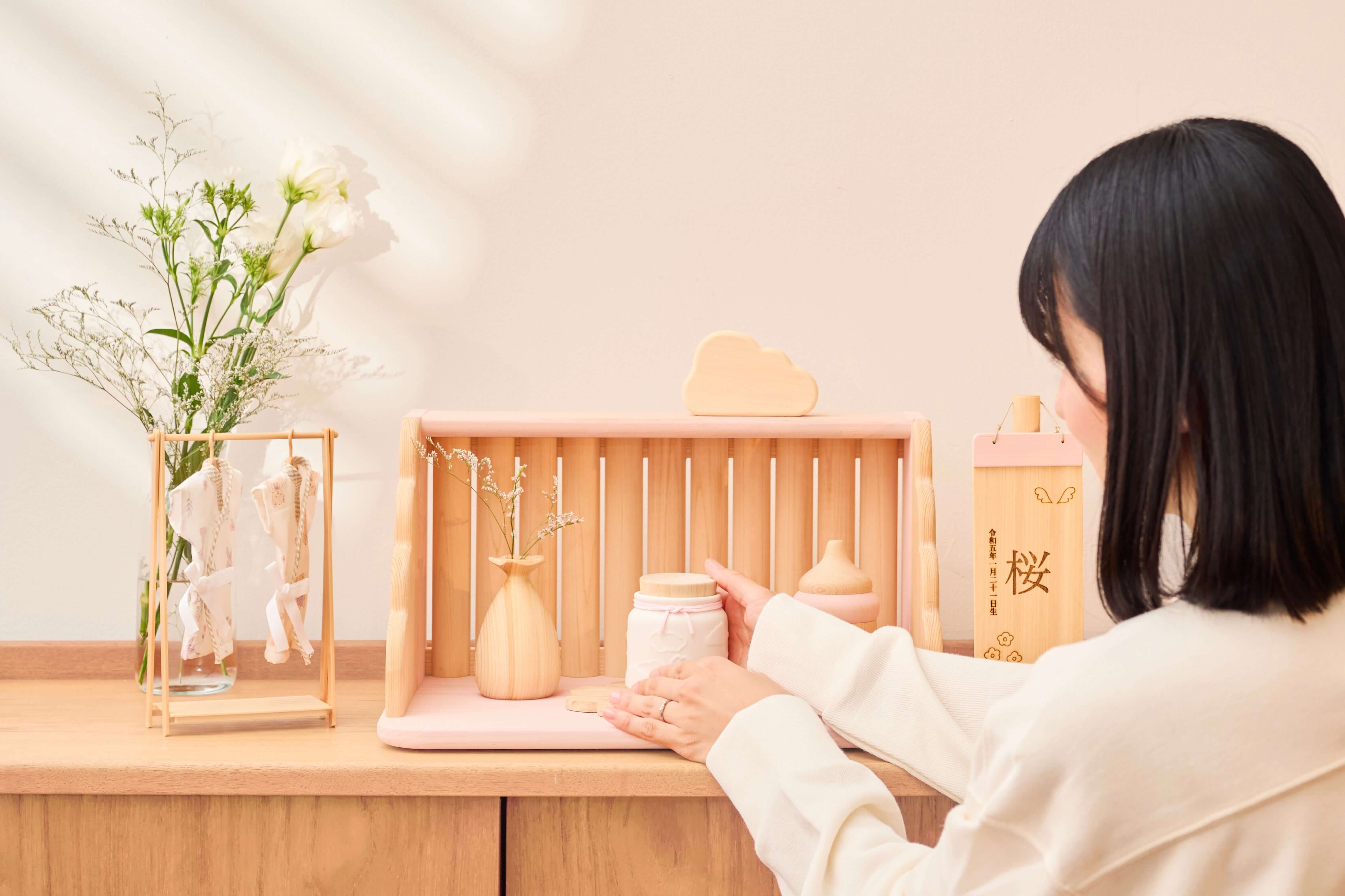 赤ちゃんのお骨壷が飾られたメモリアルスペースでお世話をする人