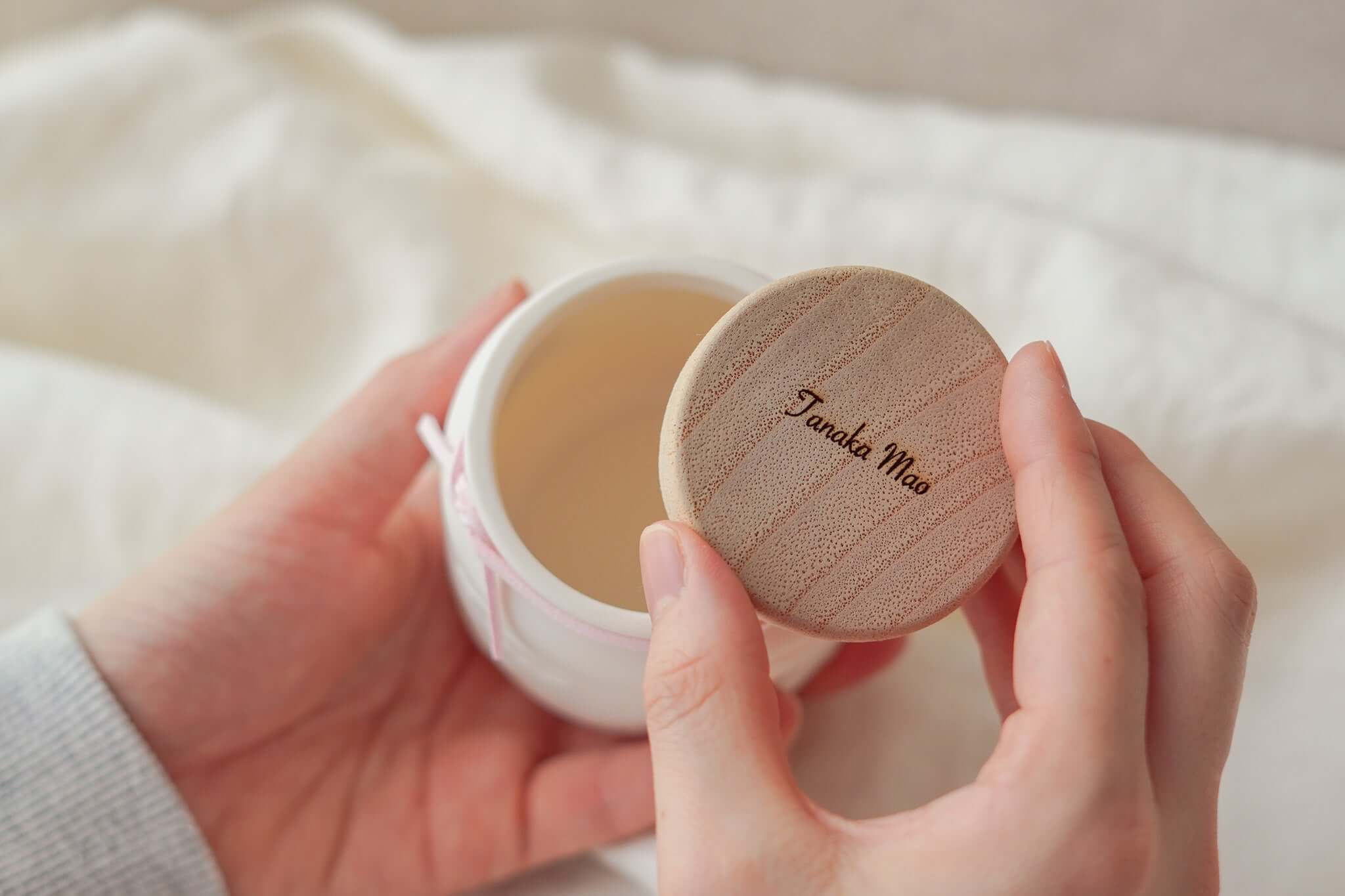 赤ちゃんのお骨壷の蓋を開ける手元の画像。かわいらしいデザインと温もりを感じる。