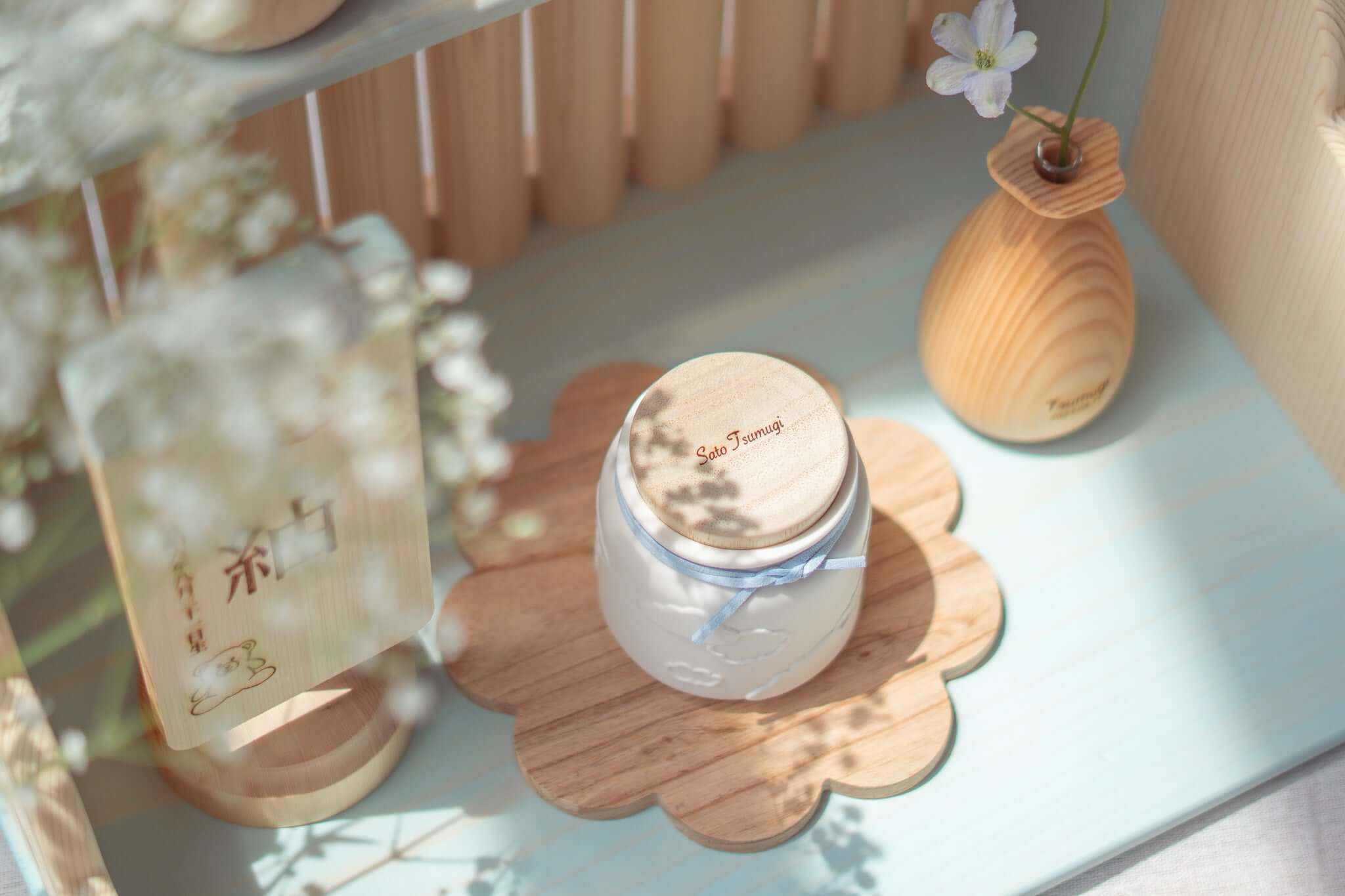 赤ちゃんのお骨壷を優しく包む天使のうつわ、木製プレートの上に置かれたデザイン