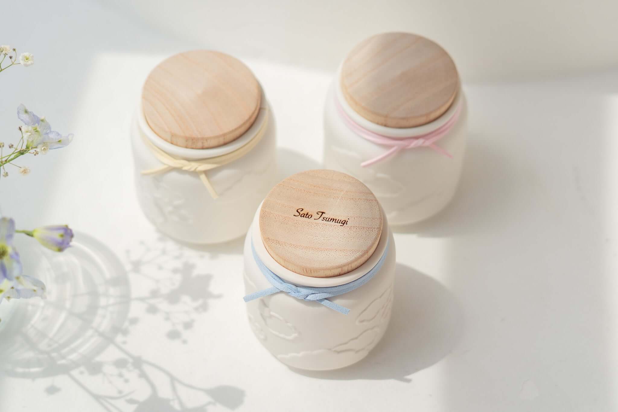 赤ちゃんのお骨壷-天使のうつわ-の繊細なデザインの陶器製骨壷、木の蓋とカラフルなリボン付き